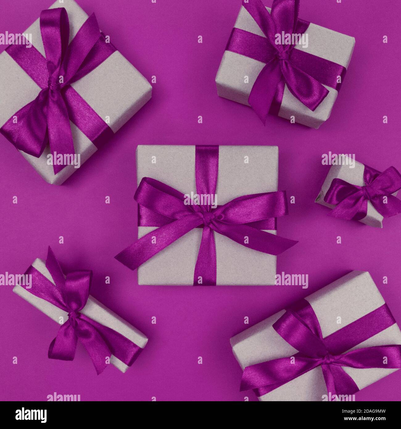 Geschenkschachteln in Bastelpapier mit violetten Bändern und Schleifen verpackt. Festliche einfarbige flache Lay. Stockfoto