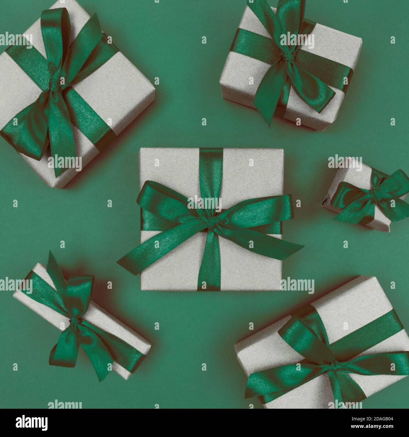 Geschenkschachteln in Bastelpapier mit grünen Bändern und Schleifen verpackt. Festliche einfarbige flache Lay. Stockfoto