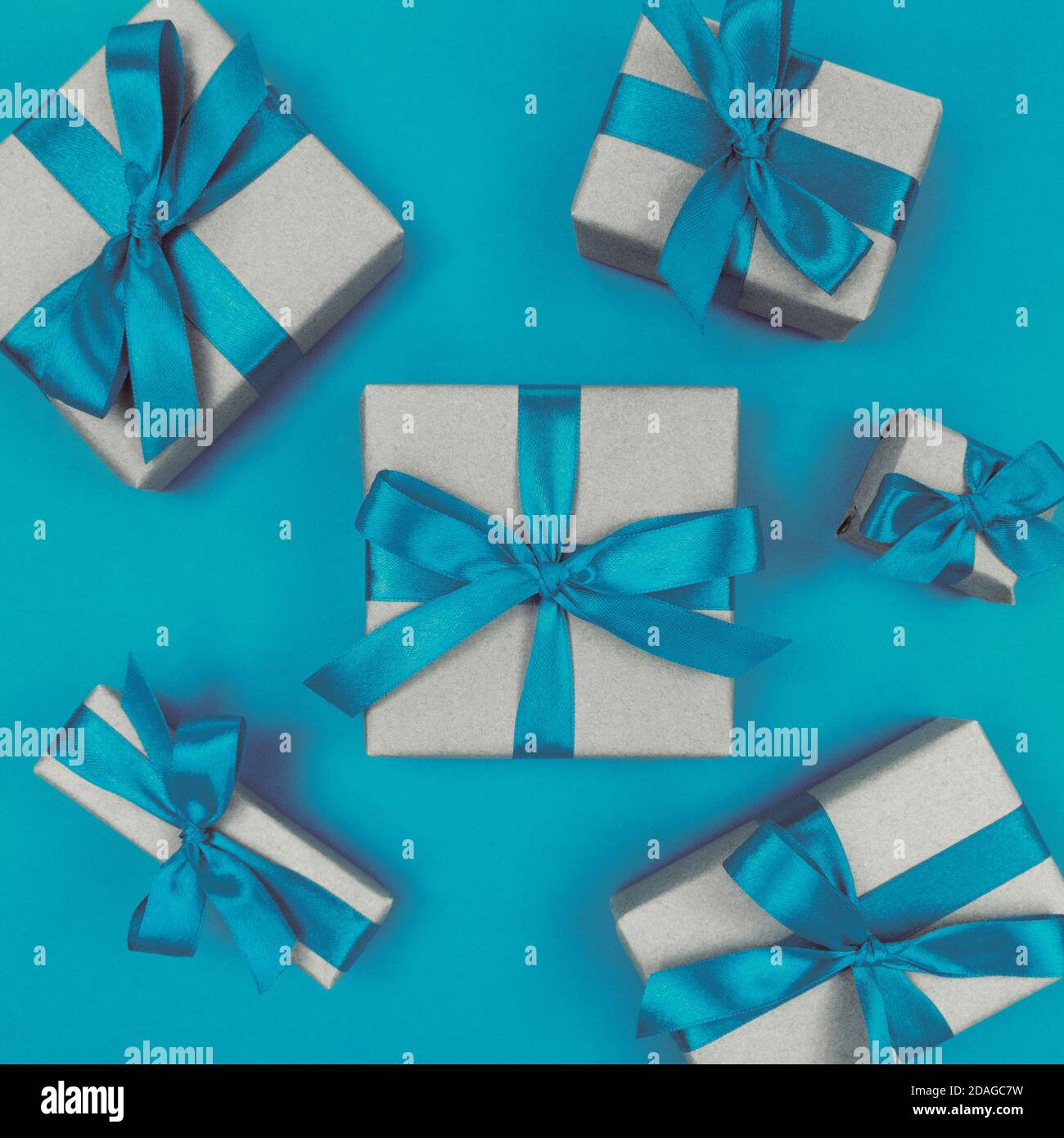 Geschenkschachteln in Bastelpapier mit blauen Bändern und Schleifen verpackt. Festliche einfarbige flache Lay. Stockfoto