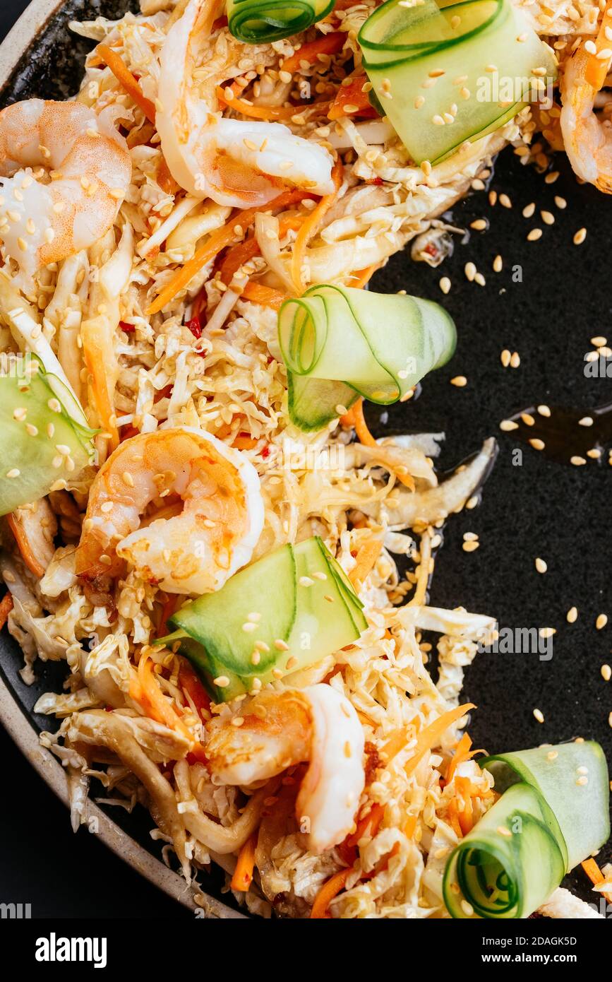 Asiatischer Gemüsesalat mit Garnelen auf schwarzem Hintergrund Stockfoto