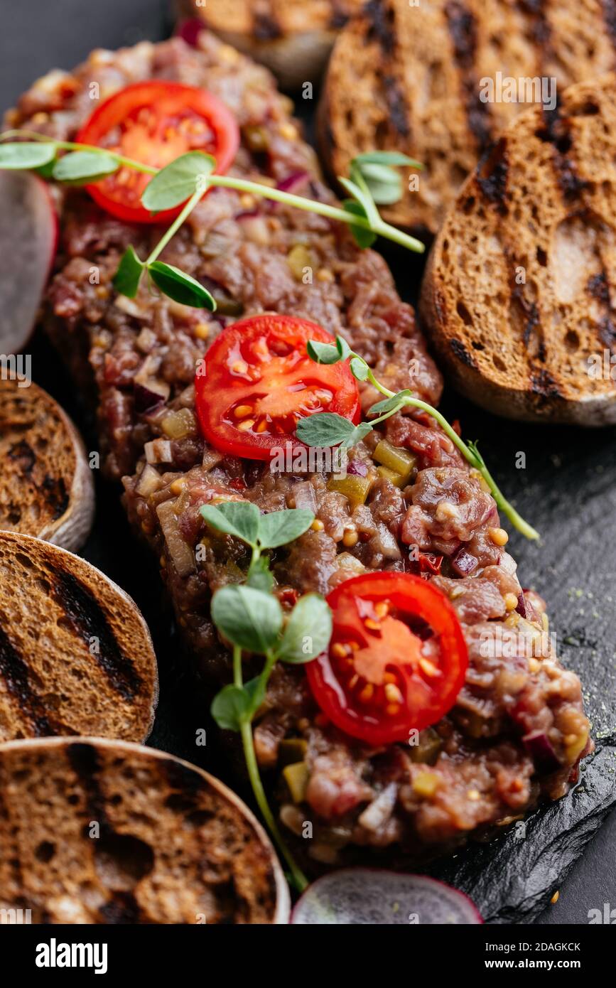 Rindertartare mit Roggencroutons auf schwarzem Hintergrund Stockfoto