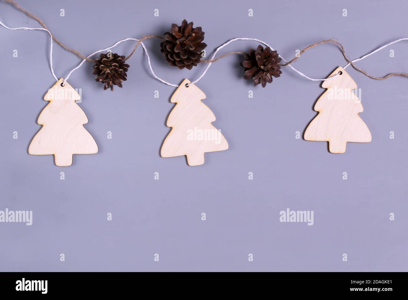 Neujahrsgirlande aus Holzbäumen und Kegeln auf grauem Hintergrund. Natürliches Weihnachtsdekor-Konzept. Speicherplatz kopieren. Draufsicht. Stockfoto