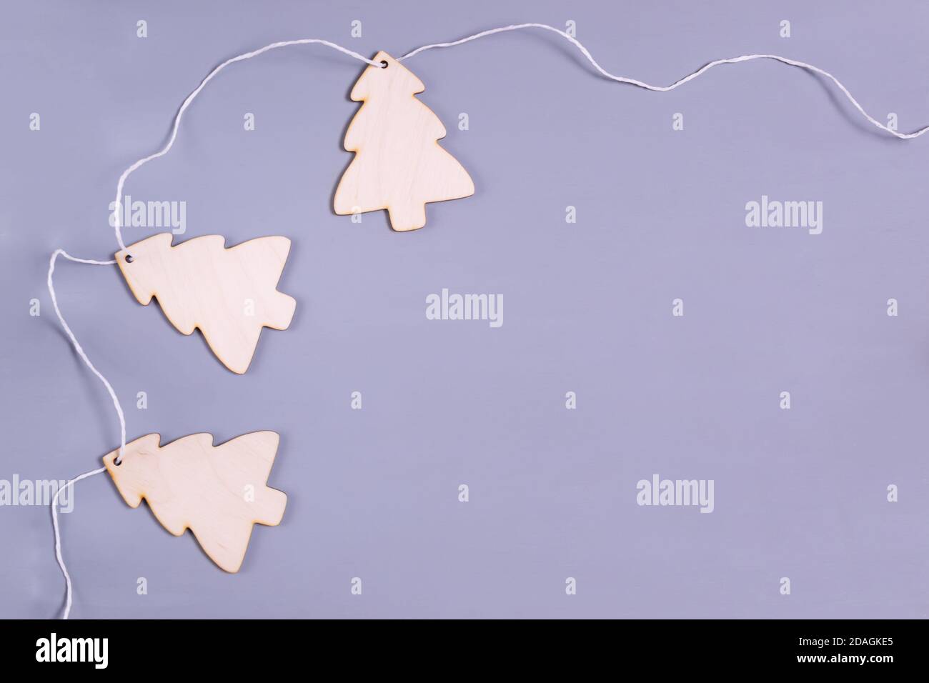 Neujahrsgirlande aus hölzernen Weihnachtsbäumen auf grauem Hintergrund. Natürliches Weihnachtsdekor-Konzept. Speicherplatz kopieren. Draufsicht. Minimalismus. Stockfoto