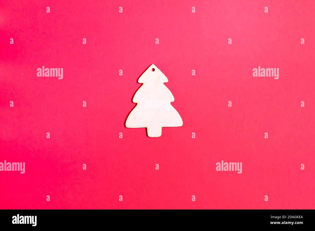 Hölzerner Weihnachtsbaum Spielzeug auf einem roten Hintergrund. Natürliches Weihnachtsdekor-Konzept. Speicherplatz kopieren. Draufsicht. Horizontale Ausrichtung. Minimalismus. Stockfoto