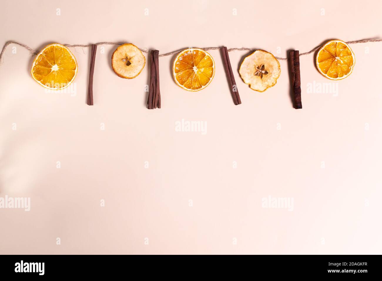 Festliche Girlande aus Zimtstangen, getrockneten Orangen und Äpfeln. Konzept für natürliche Weihnachtsdekorationen. Draufsicht. Speicherplatz kopieren. Stockfoto