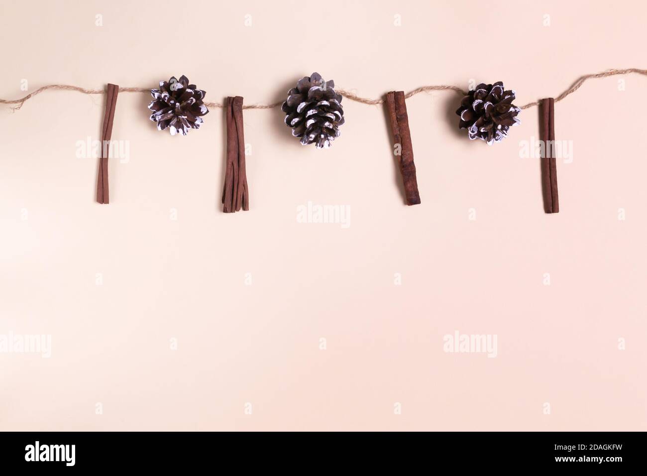 Festliche Girlande aus Zimtstangen und Tannenzapfen. Konzept für natürliche Weihnachtsdekorationen. Draufsicht. Speicherplatz kopieren. Stockfoto