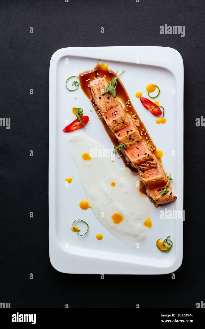 Gegrillter Lachs mit Sauce auf einem weißen Teller Stockfoto