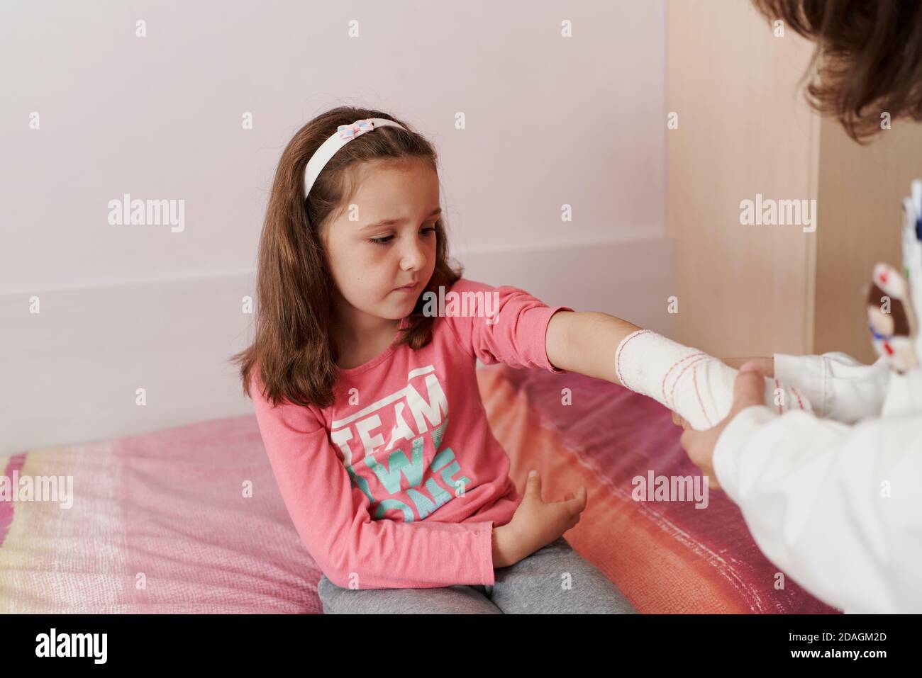 Ärztin verband den Arm eines kleinen Mädchens in ihrem Zimmer. Hausarzt Konzept Stockfoto