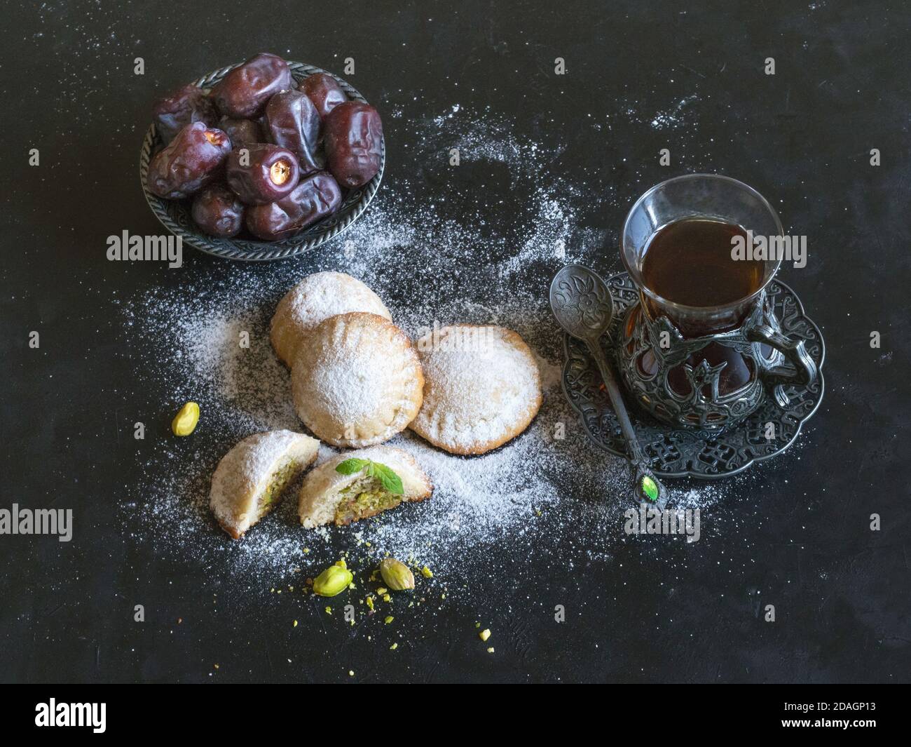 Ägyptische Kekse 'Kahk El Eid' mit Datteln und einer Tasse Tee auf einem schwarzen Tisch serviert. Cookies von El Fitr Islamischen Fest. Stockfoto