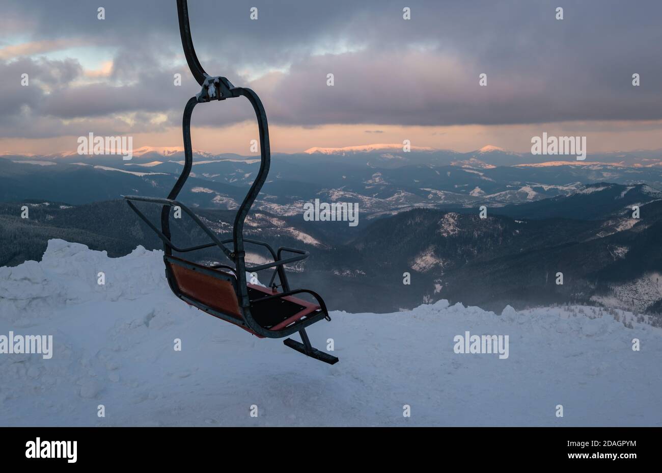 Alpine Resort Skilift mit Sitzen über den Sonnenuntergang Ski-Pisten in den Bergen bei extrem windigem Wetter Stockfoto