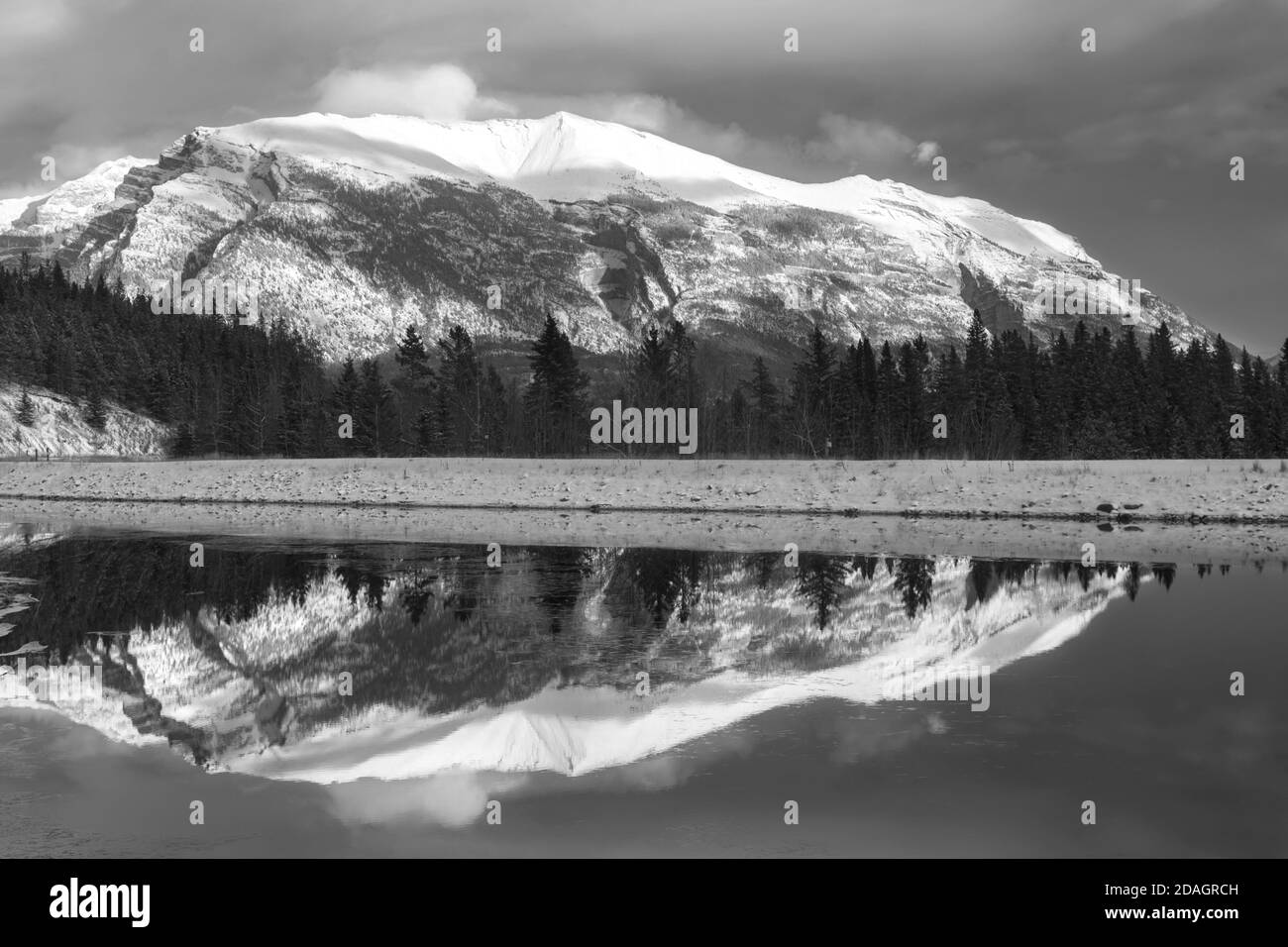 Monochrome oder Schwarzweiß-Landschaftsaufnahme des Snowy Mountain Peak, reflektiert im ruhigen und kalten Wasser des Sees über Canmore, Alberta, Kanadische Rockies Stockfoto