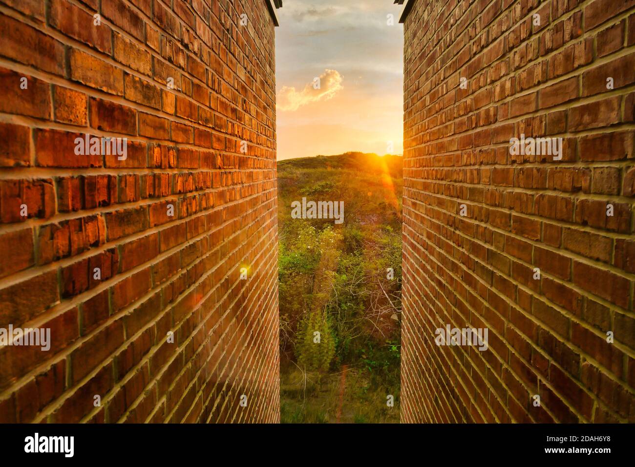 Goldener Sonnenaufgang und Landschaft zwischen Backsteinmauern schmale Öffnung. Stockfoto