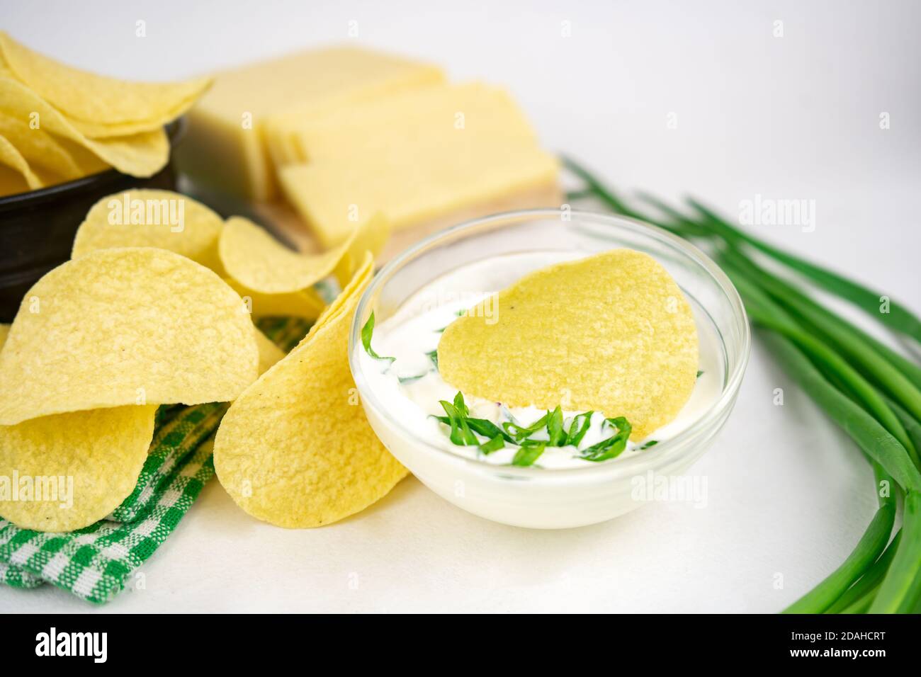 Nehmen Sie eine Chips aus einer Schüssel und tauchen Sie es in eine saure Sahne-Sauce mit grünen Zwiebeln. Stockfoto
