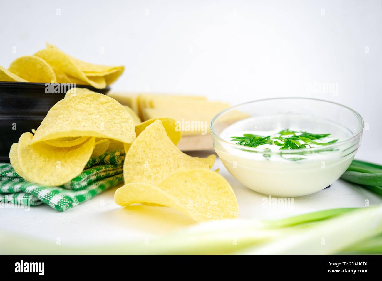 Nehmen Sie eine Chips aus einer Schüssel und tauchen Sie es in eine saure Sahne-Sauce mit grünen Zwiebeln. Stockfoto