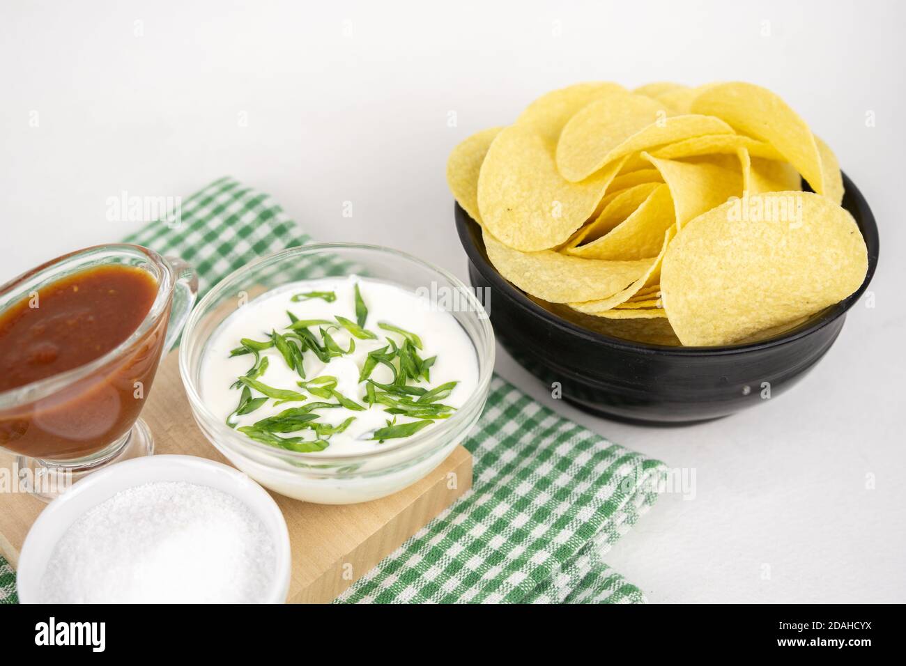 Chips mit verschiedenen Geschmacksrichtungen Konzept. Pommes mit saurer Sahne und grüner Zwiebel und roter Barbeque-Sauce. Stockfoto