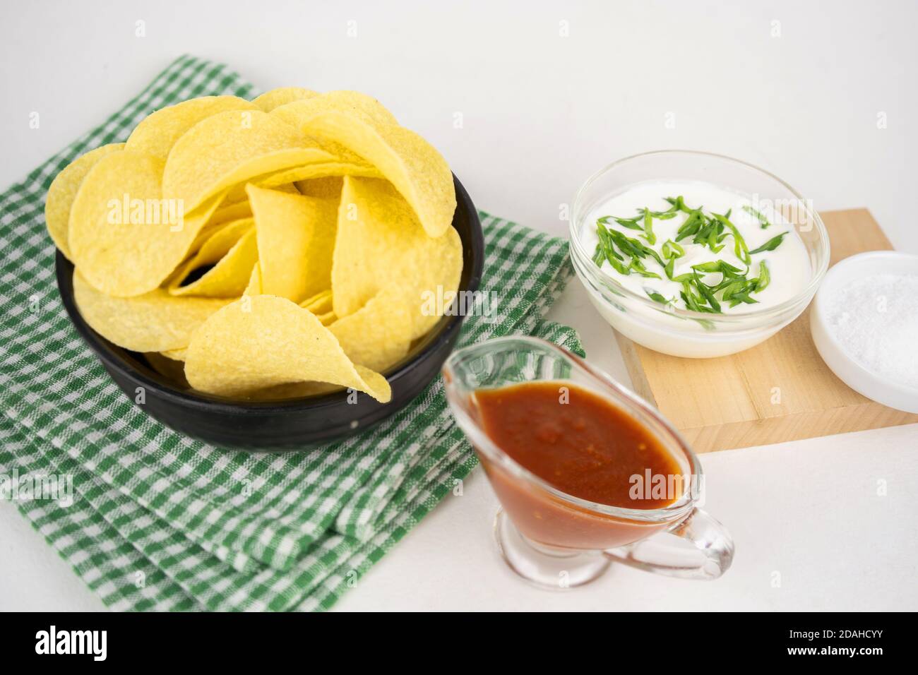Chips mit verschiedenen Geschmacksrichtungen Konzept. Pommes mit saurer Sahne und grüner Zwiebel und roter Barbeque-Sauce. Stockfoto