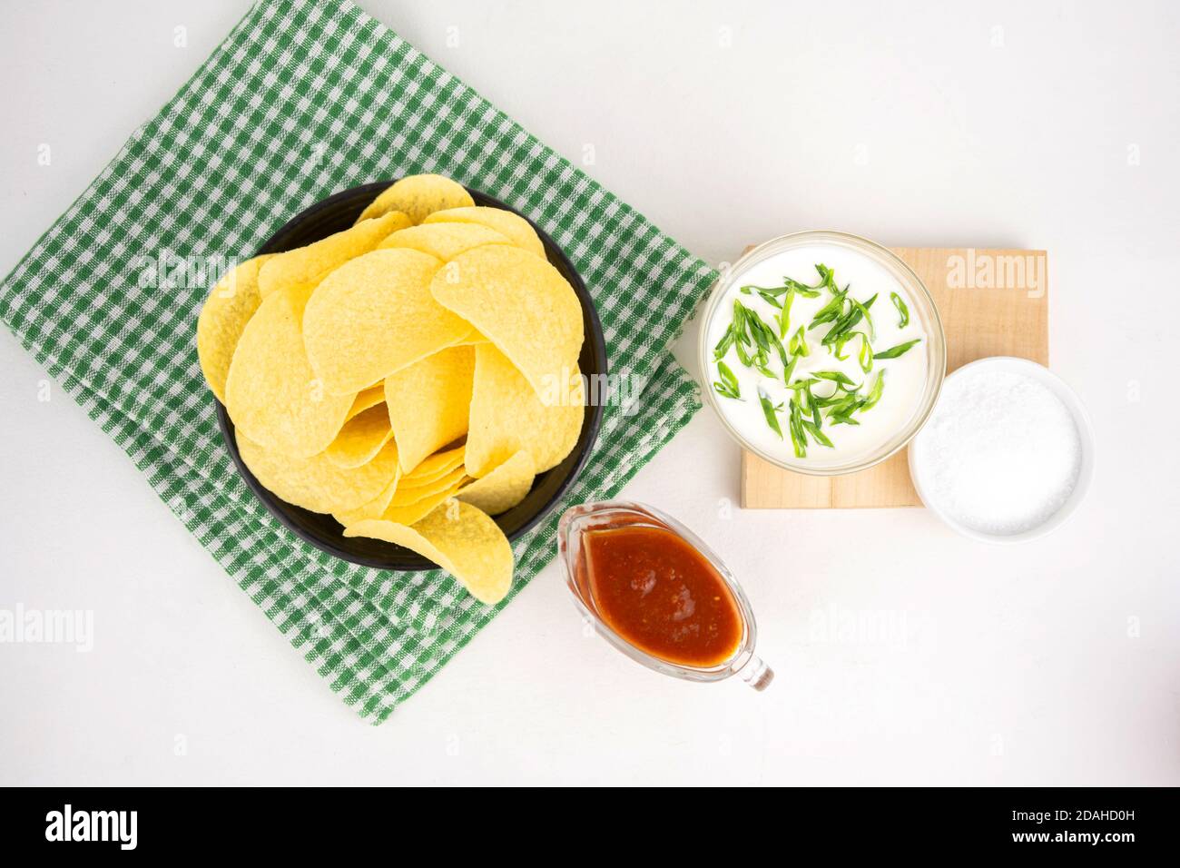 Chips mit verschiedenen Geschmacksrichtungen Konzept. Pommes mit saurer Sahne und grüner Zwiebel und roter Barbeque-Sauce. Stockfoto