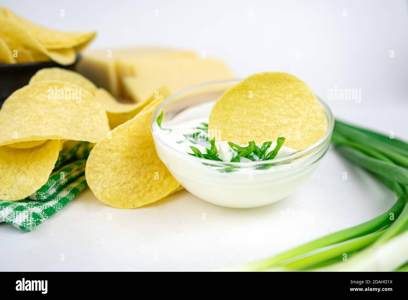 Nehmen Sie eine Chips aus einer Schüssel und tauchen Sie es in eine saure Sahne-Sauce mit grünen Zwiebeln. Stockfoto