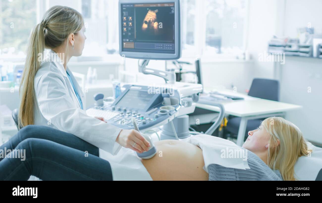 Im Krankenhaus, schwangere Frau bekommen Ultraschall-Sonogramm-Scan, Geburtshilfe erklärt ihr und ihrem unterstützenden Ehemann Verfahren. Frohe Familie Stockfoto