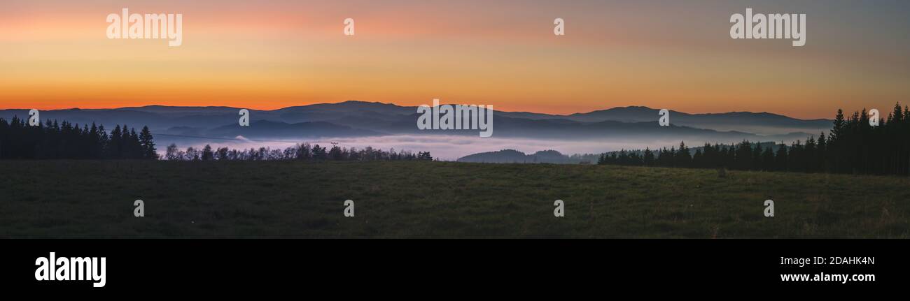 Neblige Landschaft bei Sonnenuntergang, Berge aus Nebelwolken im Hintergrund, klarer Himmel Stockfoto