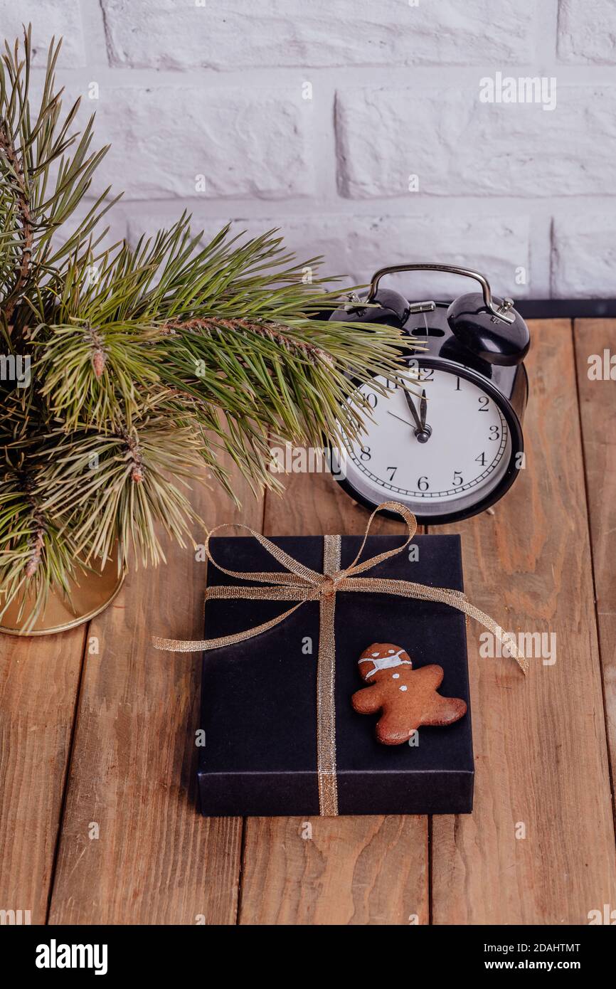 Geschäftszusammensetzung zu Weihnachten. Geschenke, schwarze und goldene Dekorationen auf Holzhintergrund. Cookies in Form eines Mannes in einer Maske. Urlaubskonzept in Stockfoto