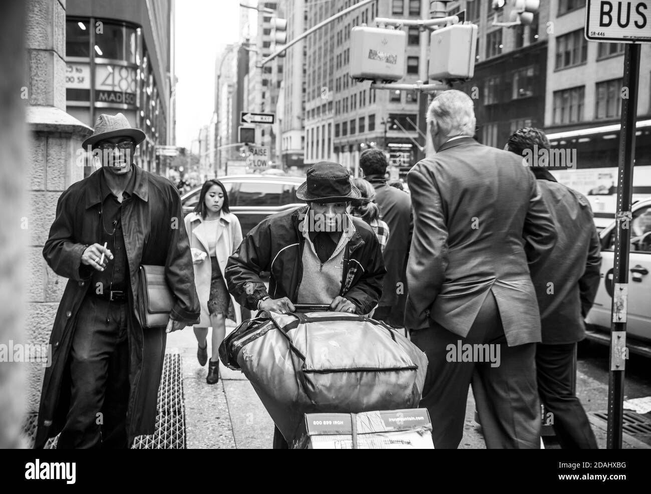 NEW YORK, USA - 03. Mai 2016: Schwarzweißbild der Madison Avenue in NYC. Manhattan Straßenszene. Zwei dunkelhäutige Männer mit einem Wagen mit dünnen beladen Stockfoto