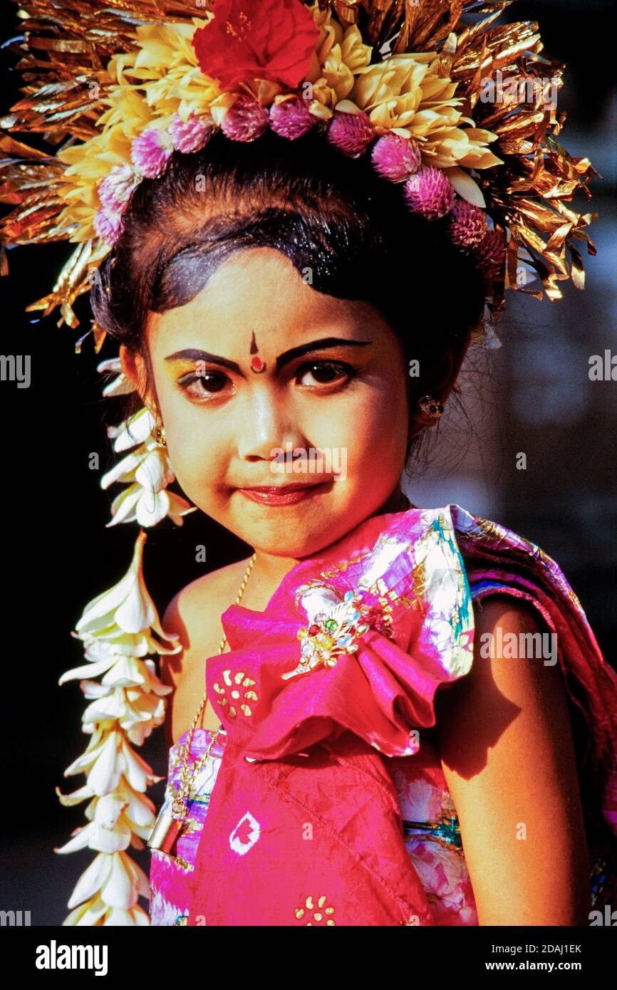 Portrait eines jungen Mädchens mit einem traditionellen Blumenschmuck und Gesicht-Make-up bei einer balinesischen Zeremonie. Bali, Indonesien Stockfoto