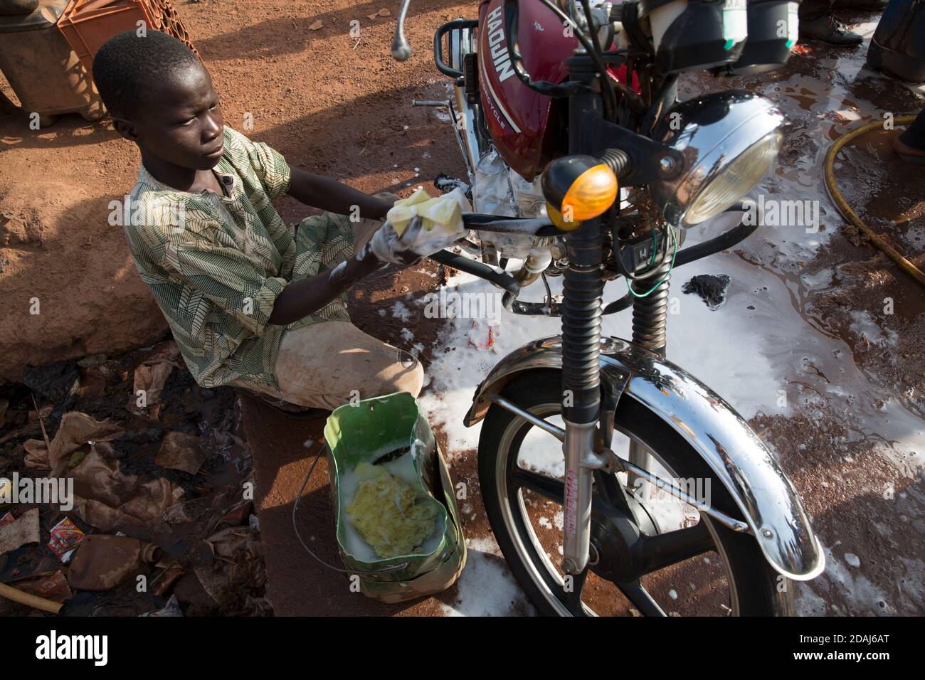 Selingue, Mali, 25. April 2015; Tiema Tounkara, 14, und Afon Troure, 19, putzen Motorräder, beide arbeiten für ihren Vater. Tiema geht zur Schule und arbeitet am Nachmittag. Afon verließ letztes Jahr die Schule. Sie berechnen 250 CFA, um jedes Fahrrad zu reinigen, und reinigen etwa 15 Fahrräder pro Tag zwischen ihnen. Stockfoto