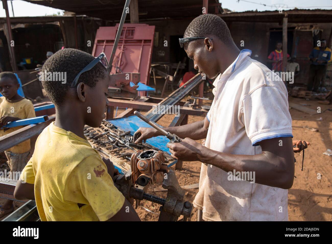 Selingue, Mali, 25. April 2015; junger Mechaniker Soungalo Bagayoko, 23, klopft an einem Motorrad-Zylinderkopf eine neue Zündkerzenbohrung an. Soungalo, der dumm ist, genießt die Arbeit. Stockfoto