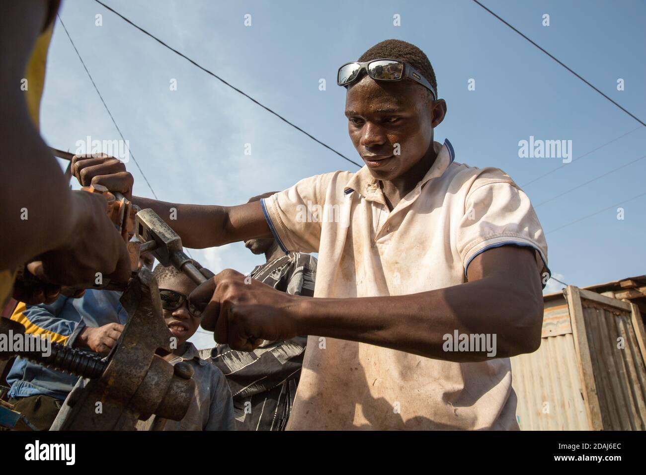Selingue, Mali, 25. April 2015; junger Mechaniker Soungalo Bagayoko, 23, klopft an einem Motorrad-Zylinderkopf eine neue Zündkerzenbohrung an. Soungalo, der dumm ist, genießt die Arbeit. Stockfoto
