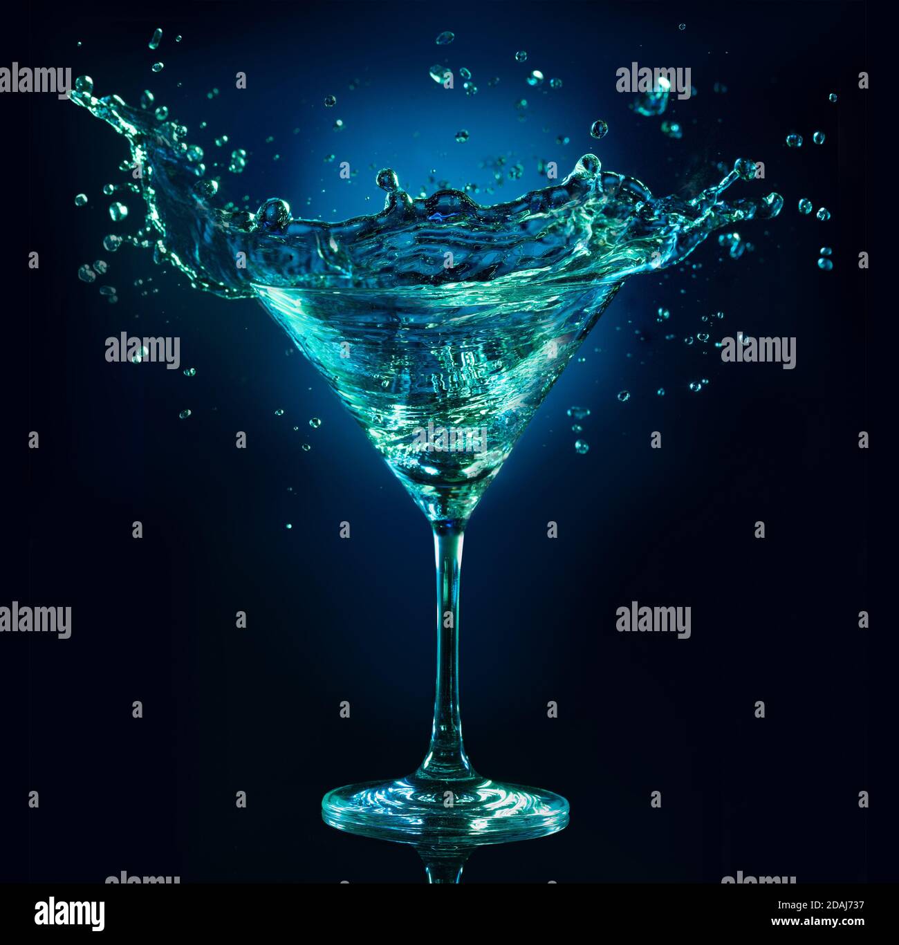 martini Cocktail spritzt auf dunkelblauem Hintergrund Stockfoto