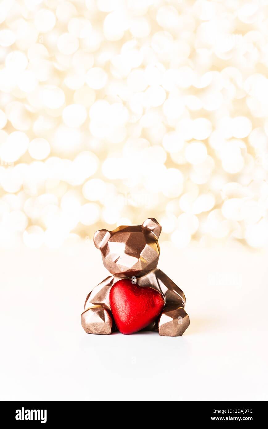 Geschenkkarte mit Schokoladenbär mit rotem Herz auf goldenem Hintergrund Weihnachtslichter Bokeh. Mockup für dekorative Gestaltung. Weihnachts- und Neujahrskonzept. Speicherplatz kopieren. Stockfoto