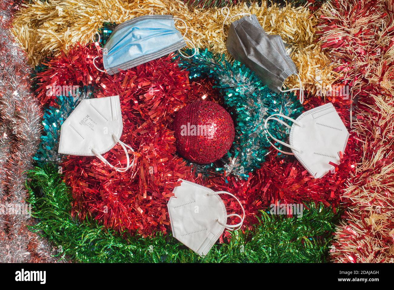 Overhead-Ansicht der Weihnachtsdekoration mit mehreren Anti-Virus-Gesichtsmasken auf der Oberseite. Persönliche Schutzausrüstung auf Partys Weihnachten. Stockfoto