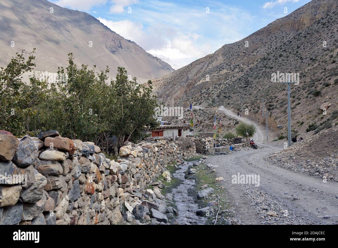 Eine unbefestigte Straße verläuft entlang eines Steinzauns im Himalaya, auf dem Weg nach Upper Mustang in Nepal. Stockfoto