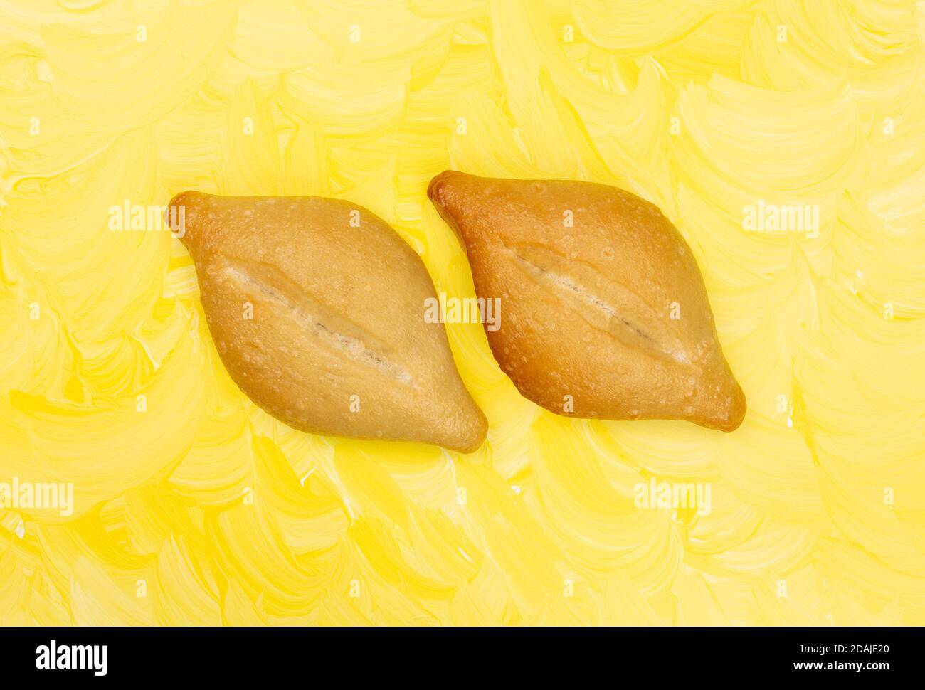 Blick von oben auf zwei frisch gebackene Bolillo Brötchen Seite an Seite auf einem gelb gestrichenen Hintergrund. Stockfoto
