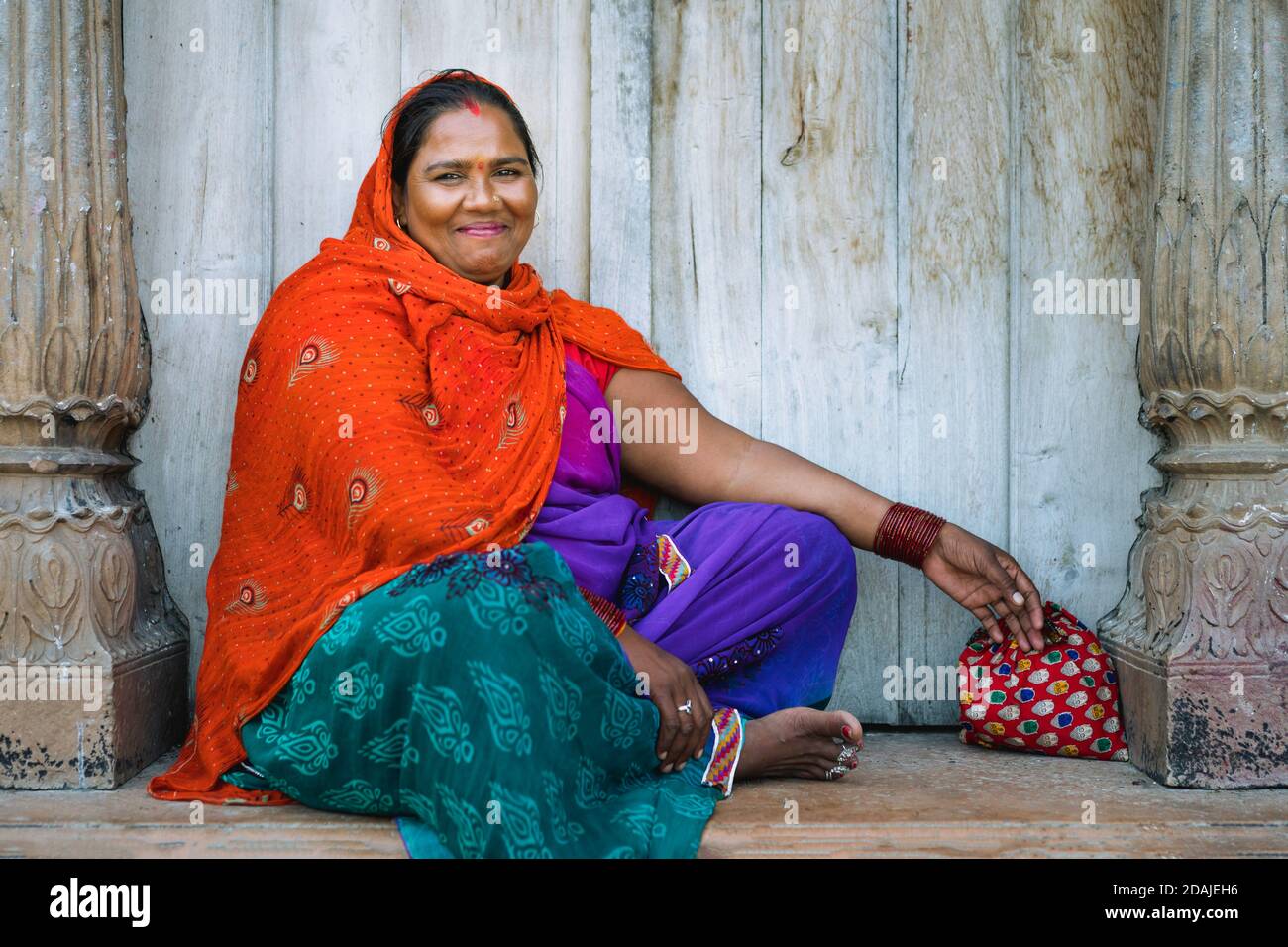 Porträt einer indischen Frau mit einem schönen Lächeln in bunten Kleidern als Kehrerin am 05. Oktober 2019 in Vrindavan, Uttar Pradesh, Indien beschäftigt. Stockfoto