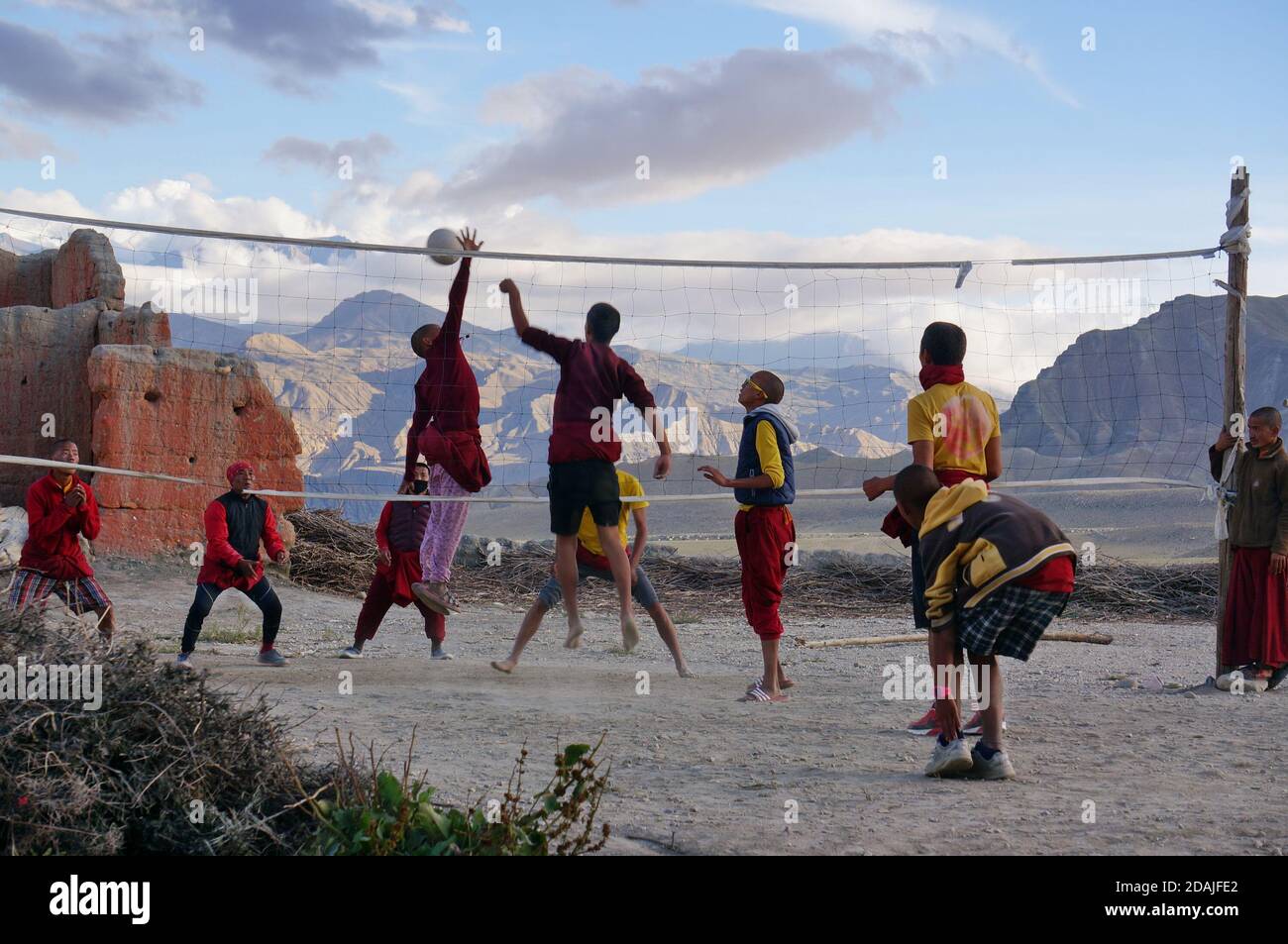 Junge Mönche spielen Volleyball während des Urlaubs, im hinteren Teil des Klosters, auf dem Hintergrund des Himalaya. Stockfoto