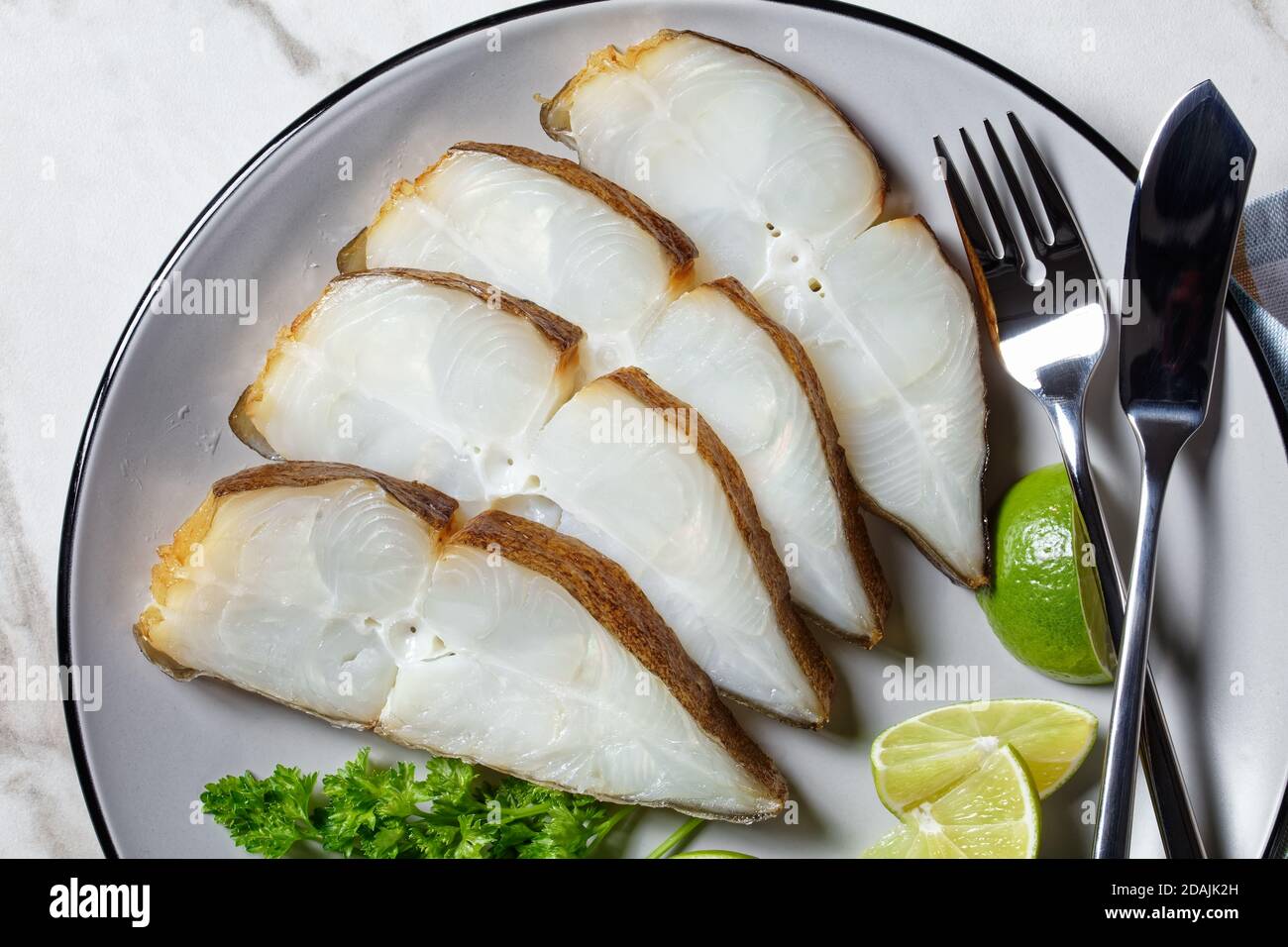 Heilbutt Fischscheiben serviert mit Kalk auf einem Teller auf einem Marmortisch, horizontale Ansicht von oben, flaches Lay, Makro Stockfoto