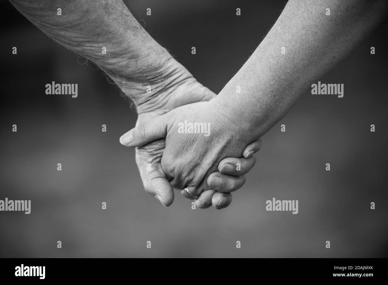 Hand eines alten Mannes und einer jungen Frau, die Hände haltend Stockfoto