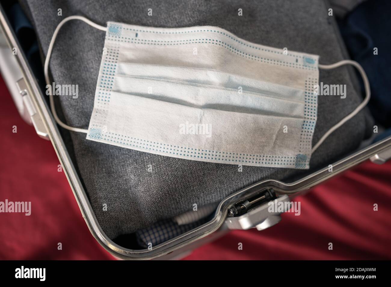 Reisen in Zeiten des Corona Virus Konzept: Ein offener Koffer mit einer gebrauchten Maske auf der Kleidung. Stockfoto