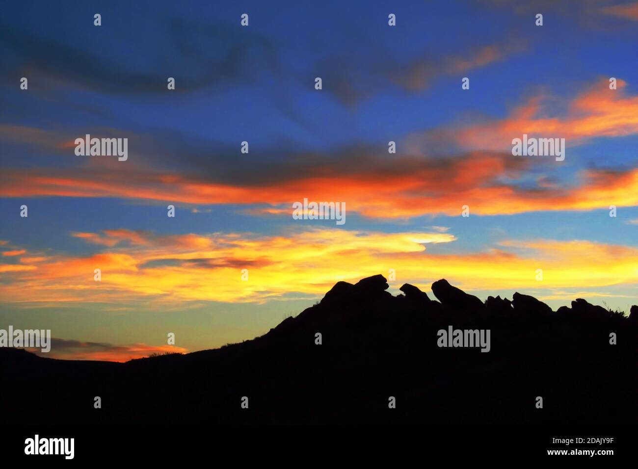 Goldene Wolken bei Sonnenuntergang, mit der Silhouette verwitterter Felsformationen im Vordergrund, fotografiert im Arches National Park, Utah, USA Stockfoto