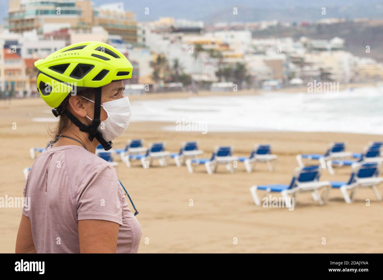 Las Palmas, Gran Canaria, Kanarische Inseln, Spanien. November 2020. Ein Radler mit Gesichtsbedeckung blickt auf einen leeren Stadtstrand in Las Palmas auf Gran Canaria, während der tropische Sturm Theta in den Norden der Kanarischen Inseln führt. Ab dem 23. November müssen Personen, die von Hochrisiko-Destinationen (einschließlich Großbritannien) auf die Kanarischen Inseln kommen, innerhalb von 72 Stunden vor ihrer Ankunft in Spanien ein negatives Covid-Ergebnis vorbringen. Kredit: Alan Dawson/Alamy Live Nachrichten Stockfoto