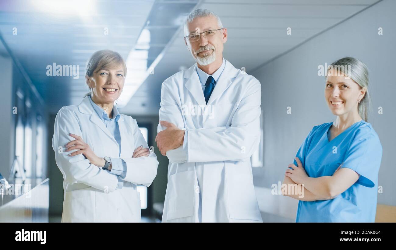 Porträt von Ärzten und Krankenschwestern posiert im Krankenhaus Gebäude, Arme gekreuzt und lächelnd. Brillante Menschen in medizinischen Fachkräften, die Leben retten. Stockfoto
