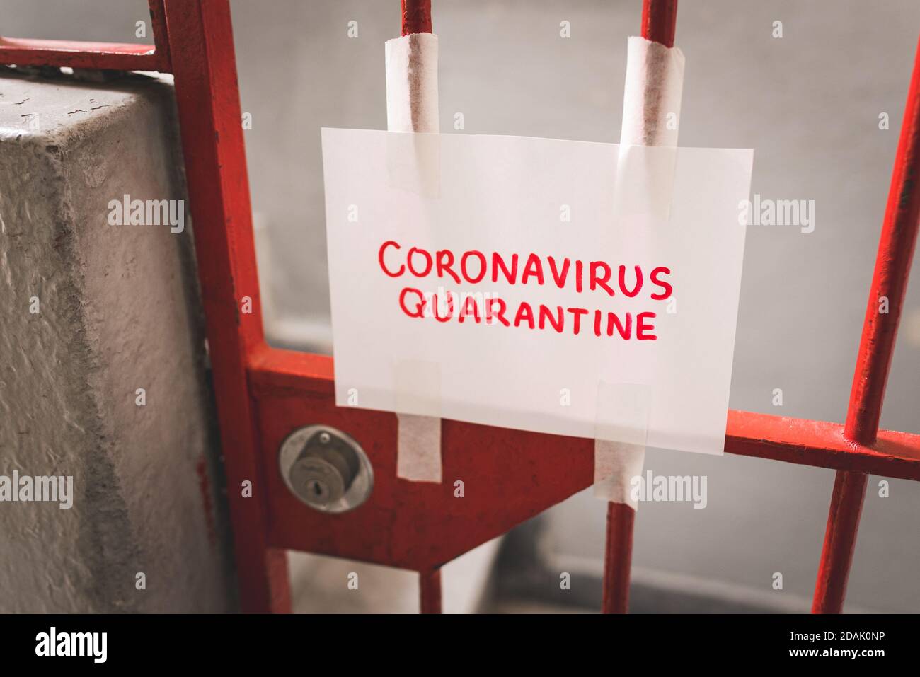 Blatt Papier, das Coronavirus-Quarantäne in roten Buchstaben aufgeklebt sagt An der verriegelten Eisentür Stockfoto