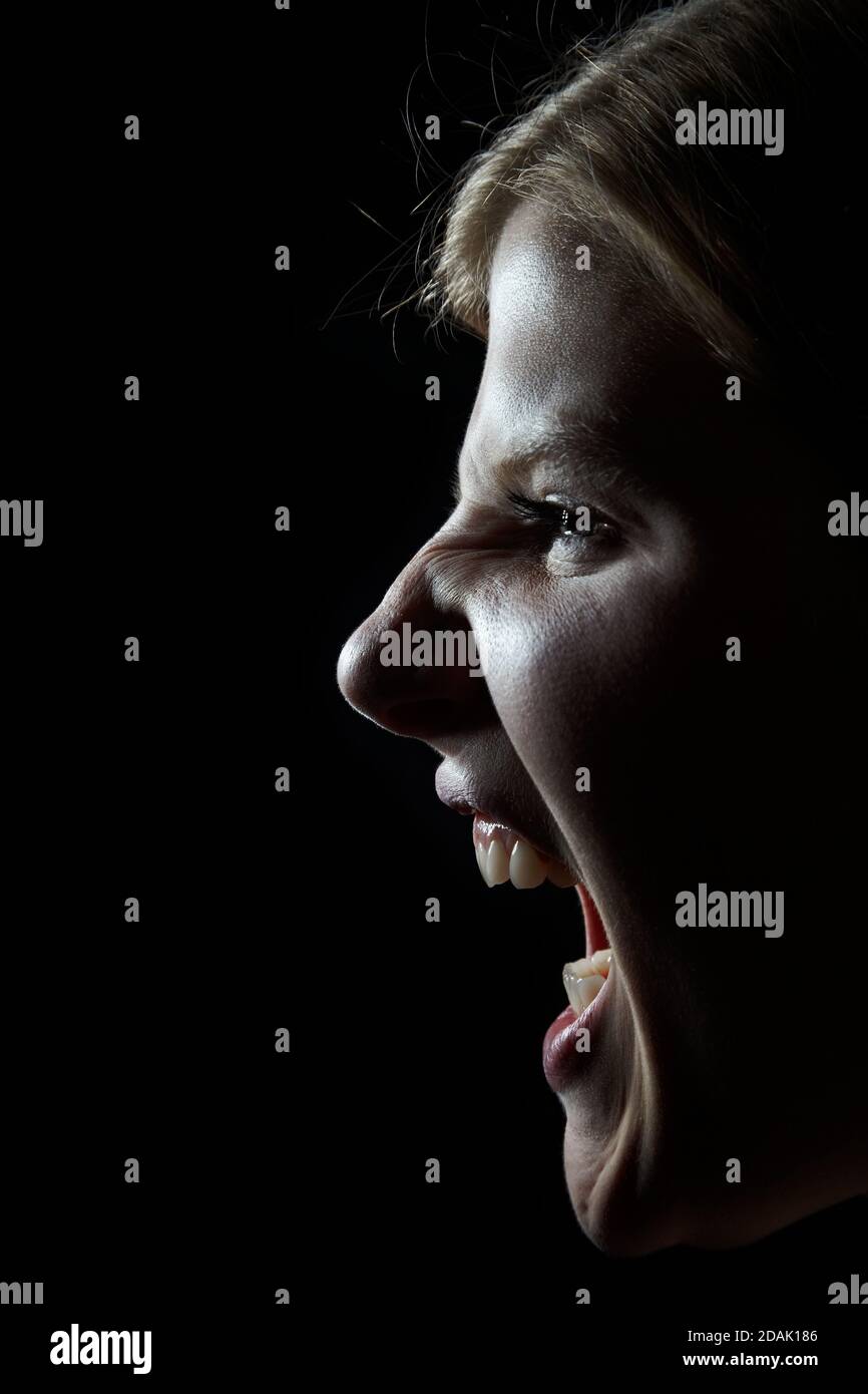 Blonde Frau schreit im Dunkeln Stockfoto