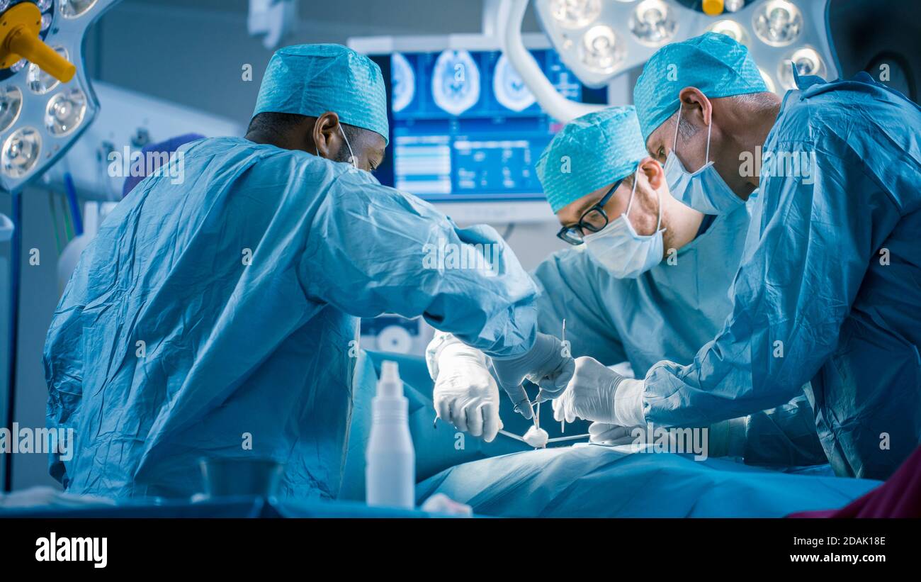 Vielfältiges Team von professionellen Chirurgen, die invasive Chirurgie an einem Patienten im Operationssaal des Krankenhauses durchführen. Chirurgen Verwenden Instrumente. Stockfoto