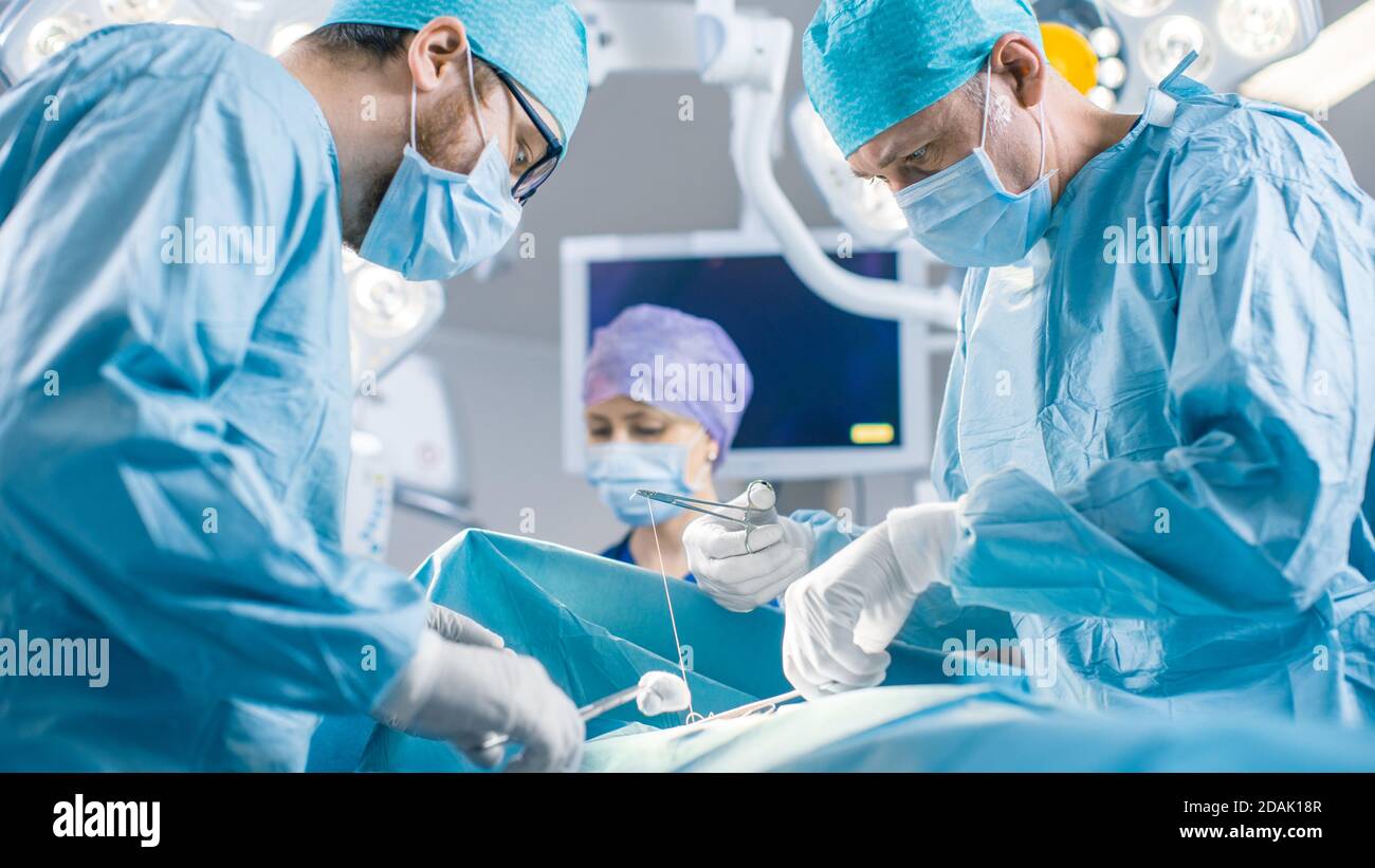 Im Operationssaal des Krankenhauses Diverse Team von professionellen Chirurgen und Krankenschwestern Naht Wunde nach erfolgreicher Operation. Stockfoto