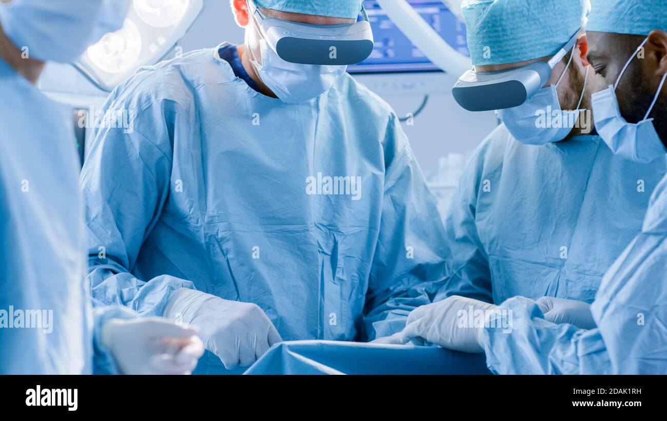 Chirurgen mit Augmented Reality Brille, um State of the Art Chirurgie in technologally Advanced Hospital durchzuführen. Ärzte und Assistenten arbeiten Stockfoto