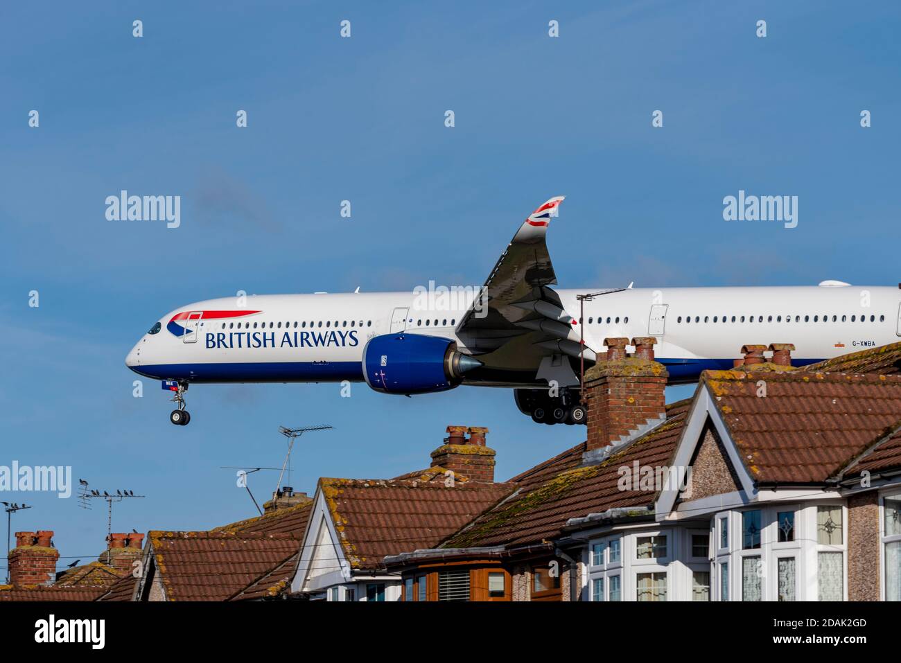 British Airways-Jet-Flugzeug auf dem Anflug auf den Flughafen London Heathrow, Großbritannien, über Dächer von Häusern in der Nähe des Flughafens zu landen. Eigenschaften unter flightpath Stockfoto