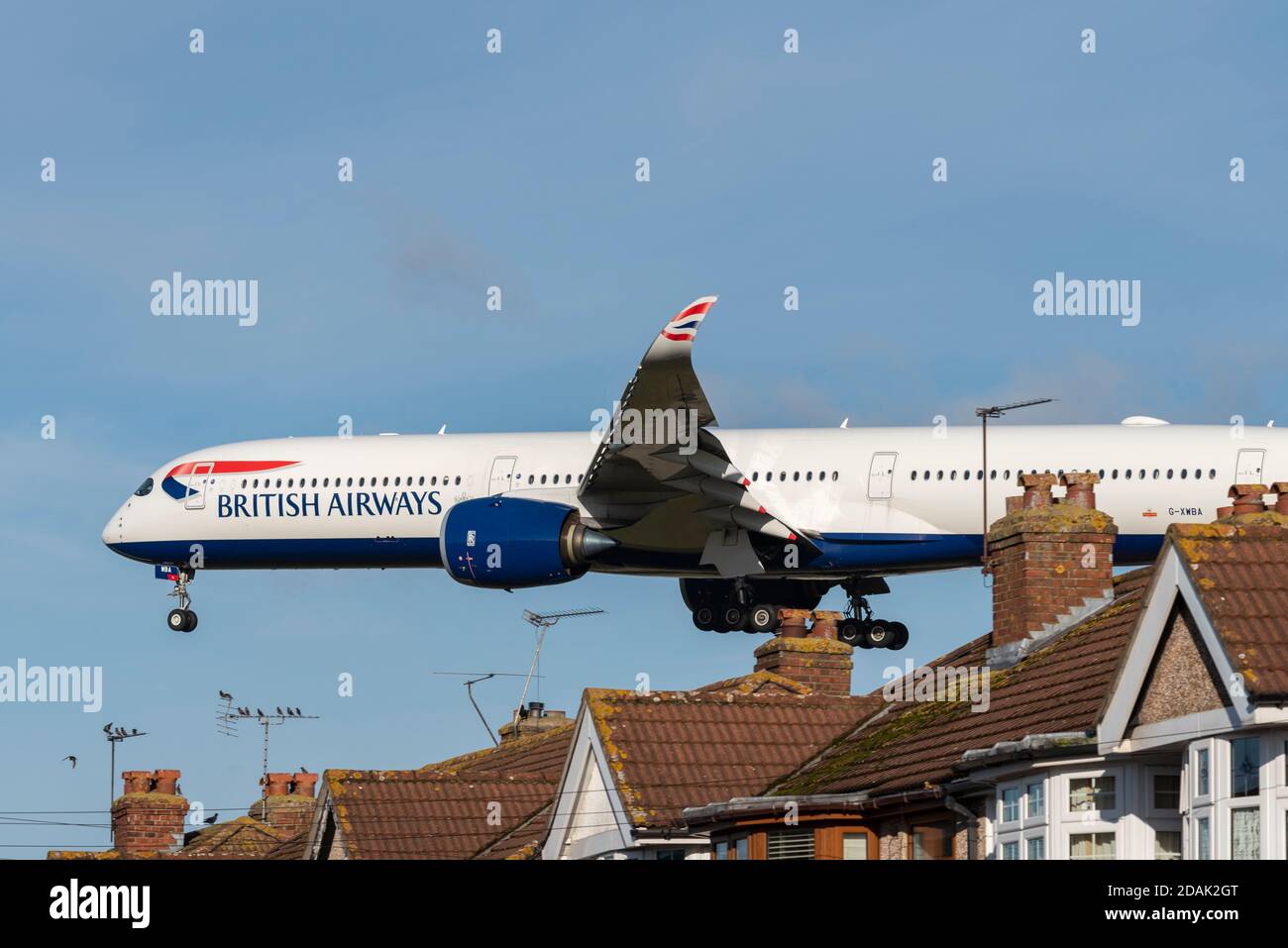 British Airways-Jet-Flugzeug auf dem Anflug auf den Flughafen London Heathrow, Großbritannien, über Dächer von Häusern in der Nähe des Flughafens zu landen. Eigenschaften unter flightpath Stockfoto
